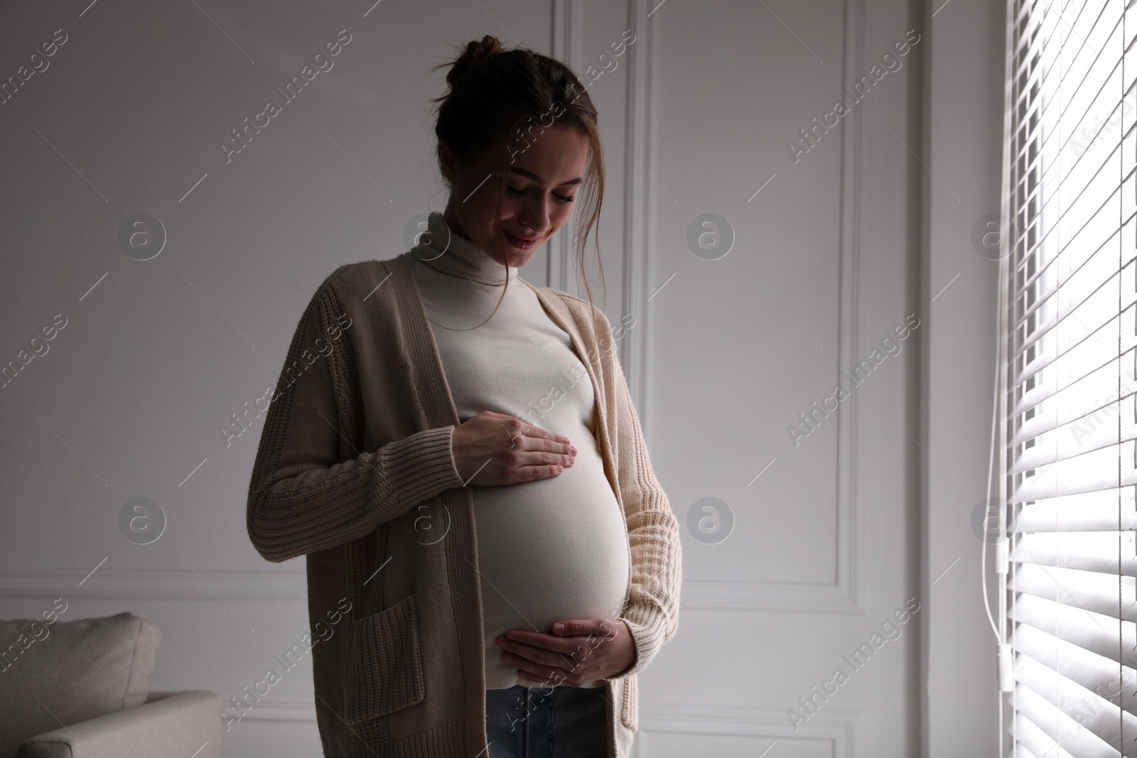 Photo of Young pregnant woman in room at home