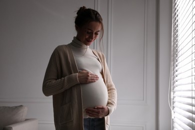 Photo of Young pregnant woman in room at home