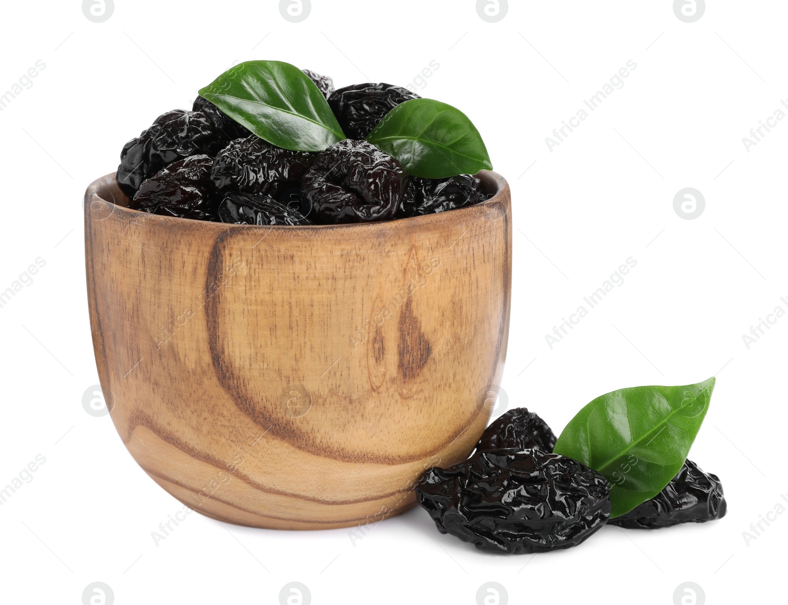 Photo of Bowl with sweet dried prunes and green leaves on white background