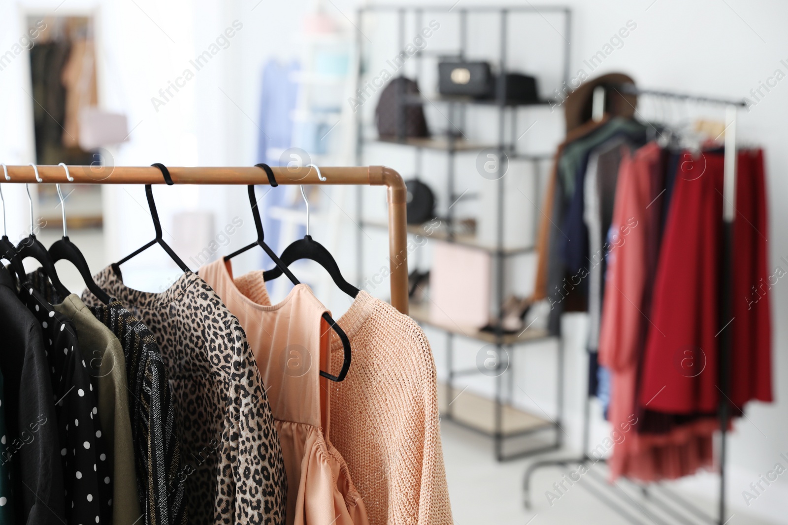 Photo of Different stylish clothes on rack in dressing room, closeup