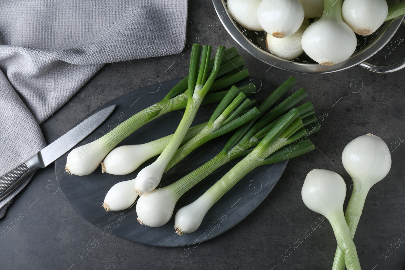 Photo of Whole green spring onions on black table, flat lay