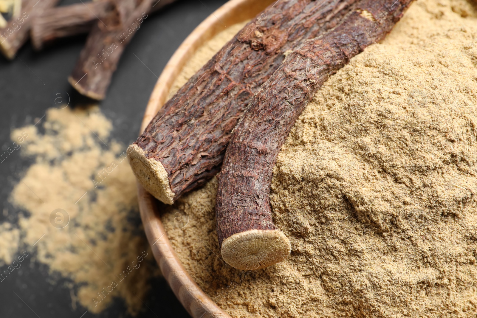 Photo of Powder and dried sticks of liquorice root in bowl, closeup