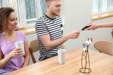 Clients using credit card machine for non cash payment in cafe