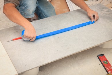 Worker making socket hole in tile indoors, closeup