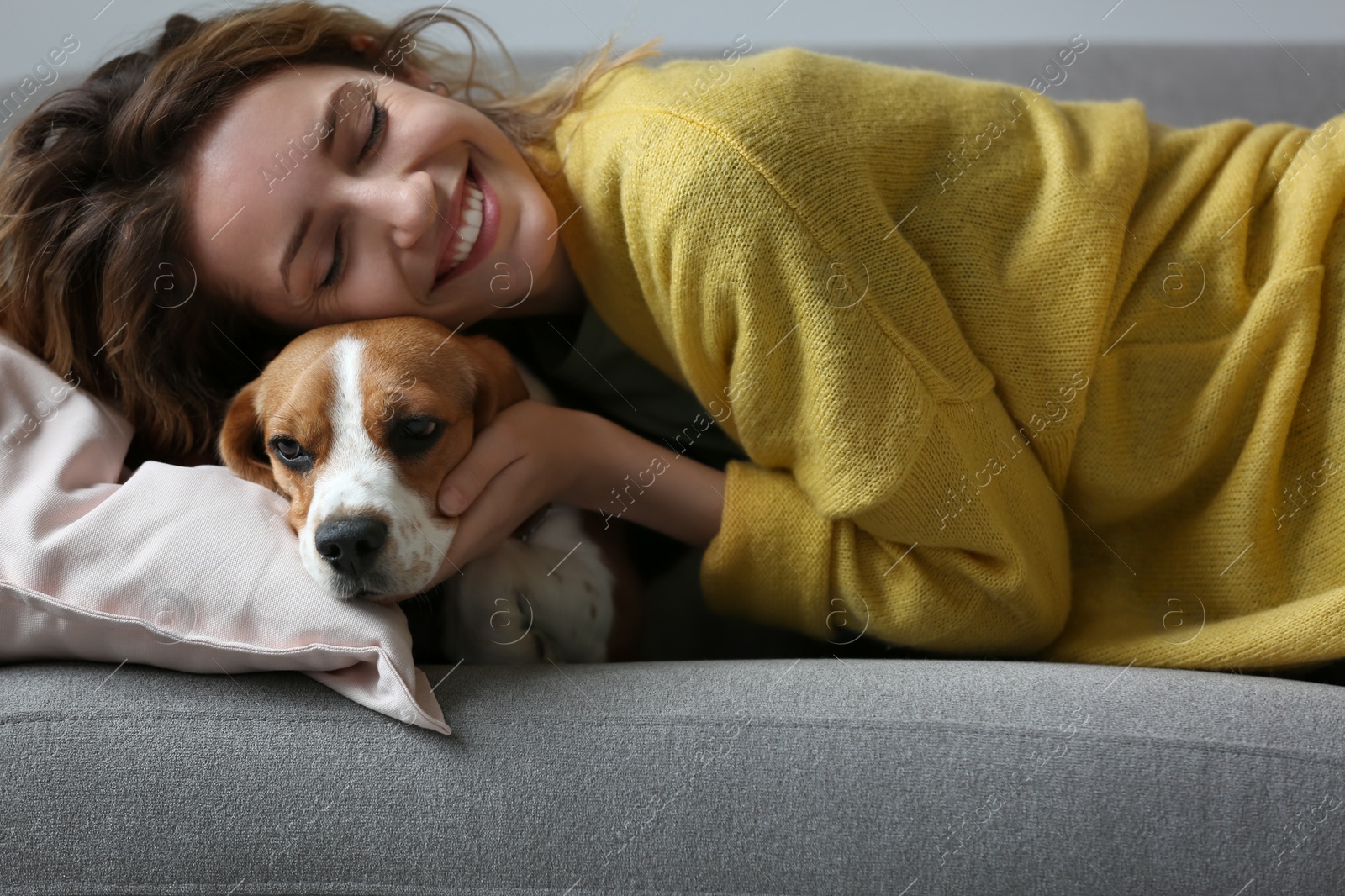 Photo of Young woman with her dog resting on sofa at home