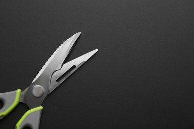 Photo of Kitchen scissors on dark background, top view. Space for text