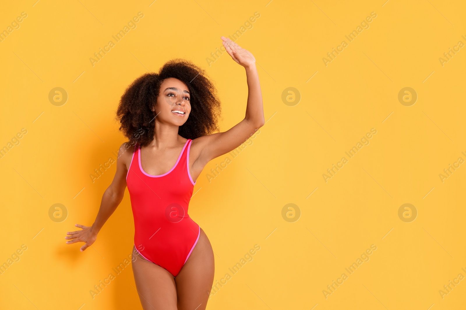 Photo of Beautiful woman in bright one-piece summer swimsuit on yellow background, space for text