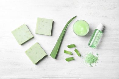 Flat lay composition with handmade soap bars and ingredients on white wooden background