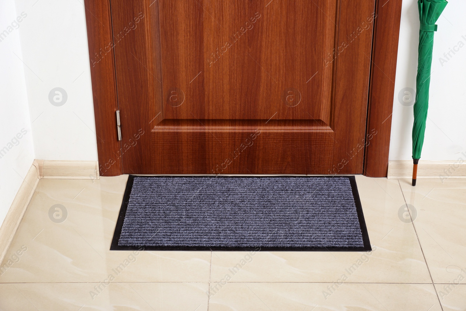 Photo of Welcome mat and umbrella at door in hall