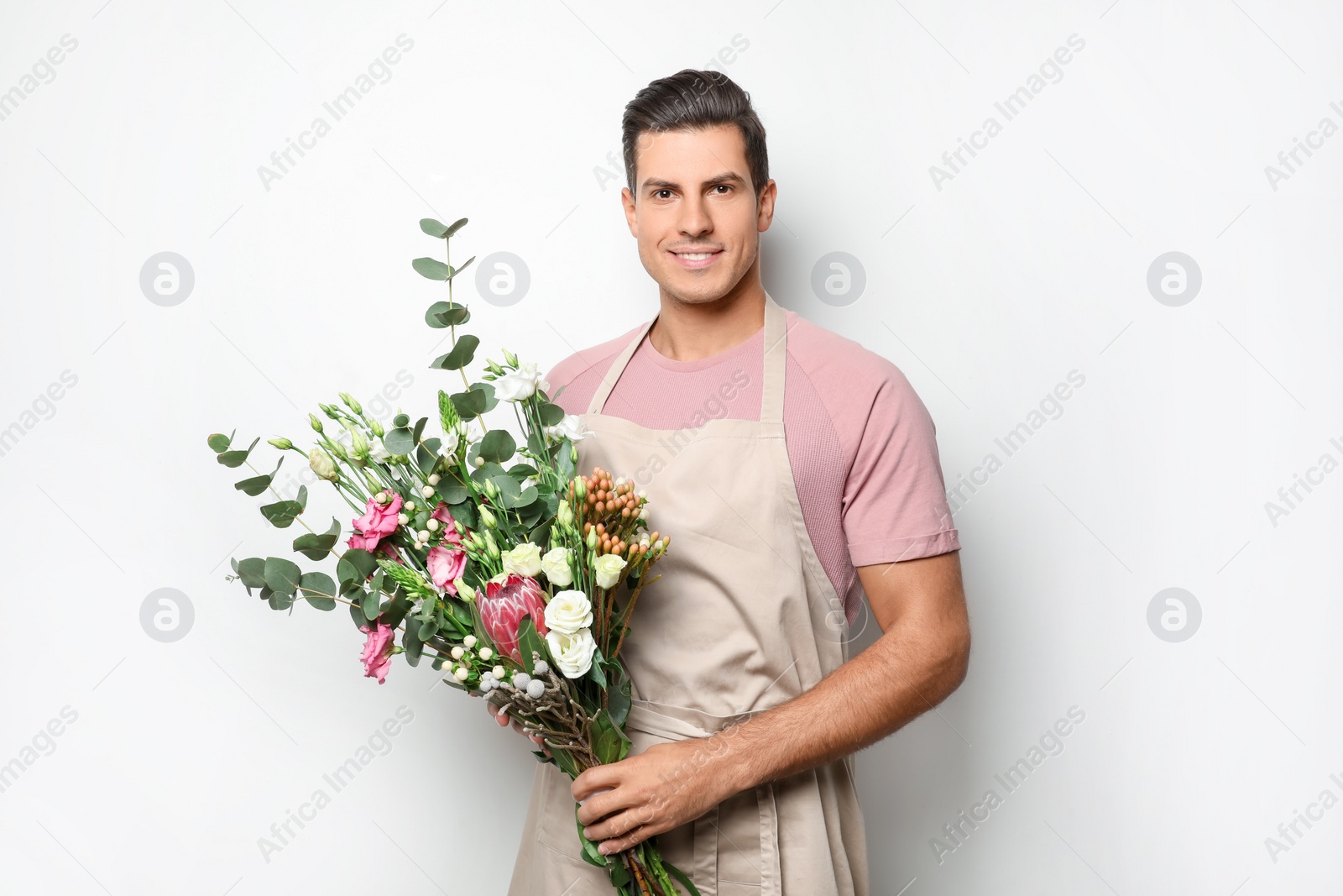 Photo of Florist with beautiful bouquet on light background