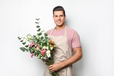 Florist with beautiful bouquet on light background