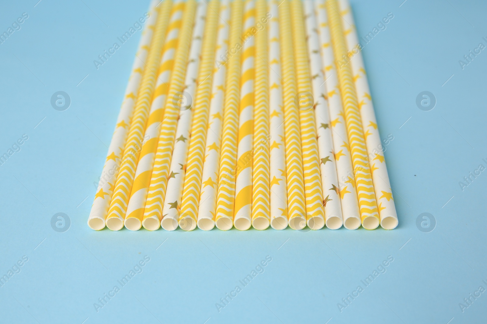 Photo of Many paper drinking straws on light blue background