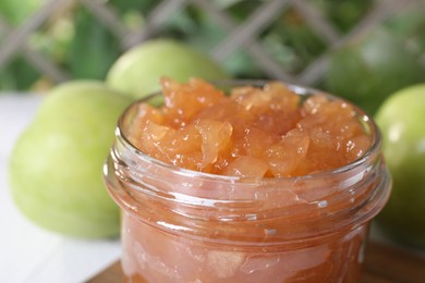 Photo of Glass jar of delicious apple jam against blurred background, closeup