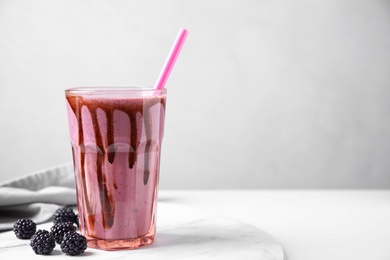 Photo of Tasty blackberry milk shake in glass on white table