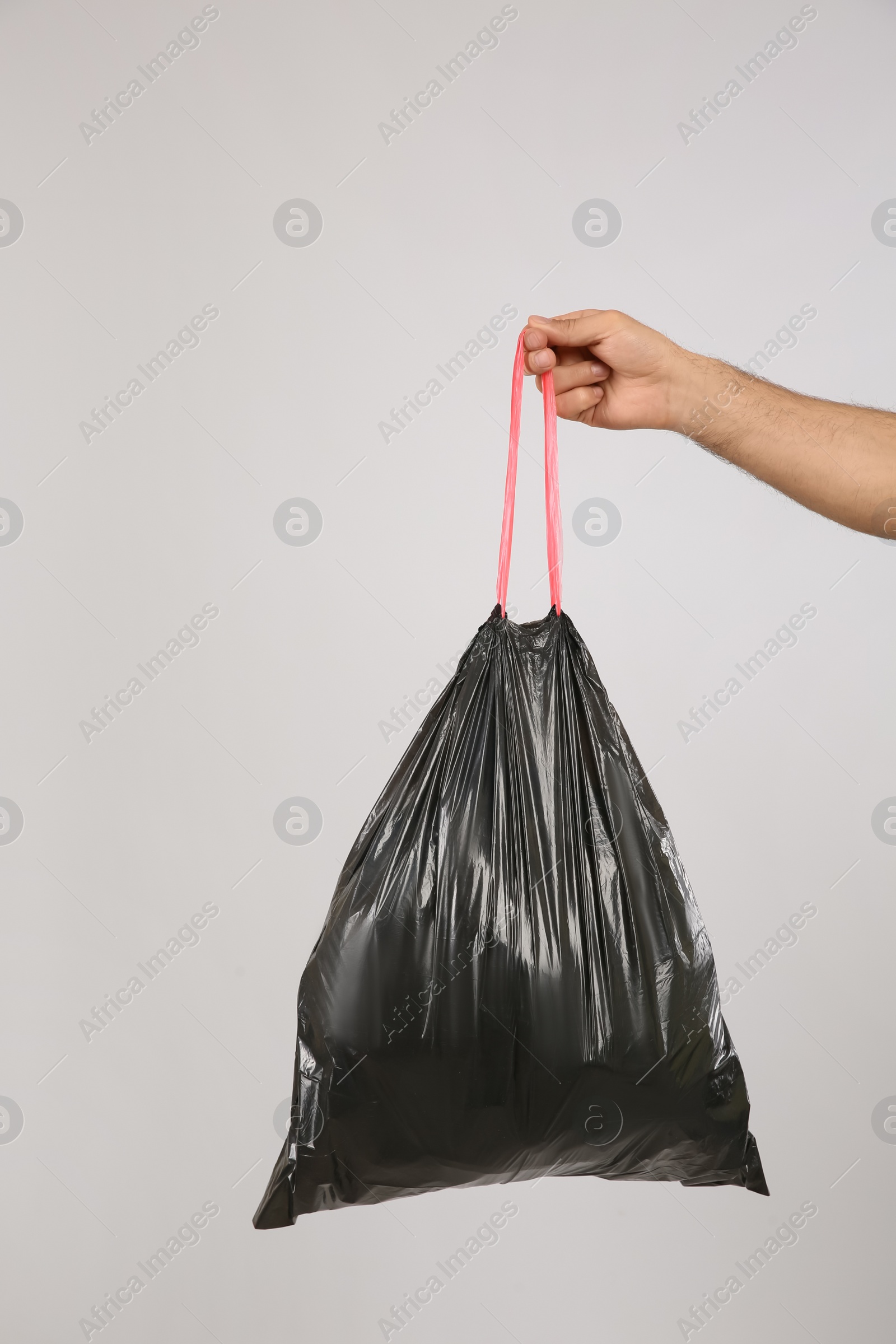 Photo of Man holding full garbage bag on light background, closeup