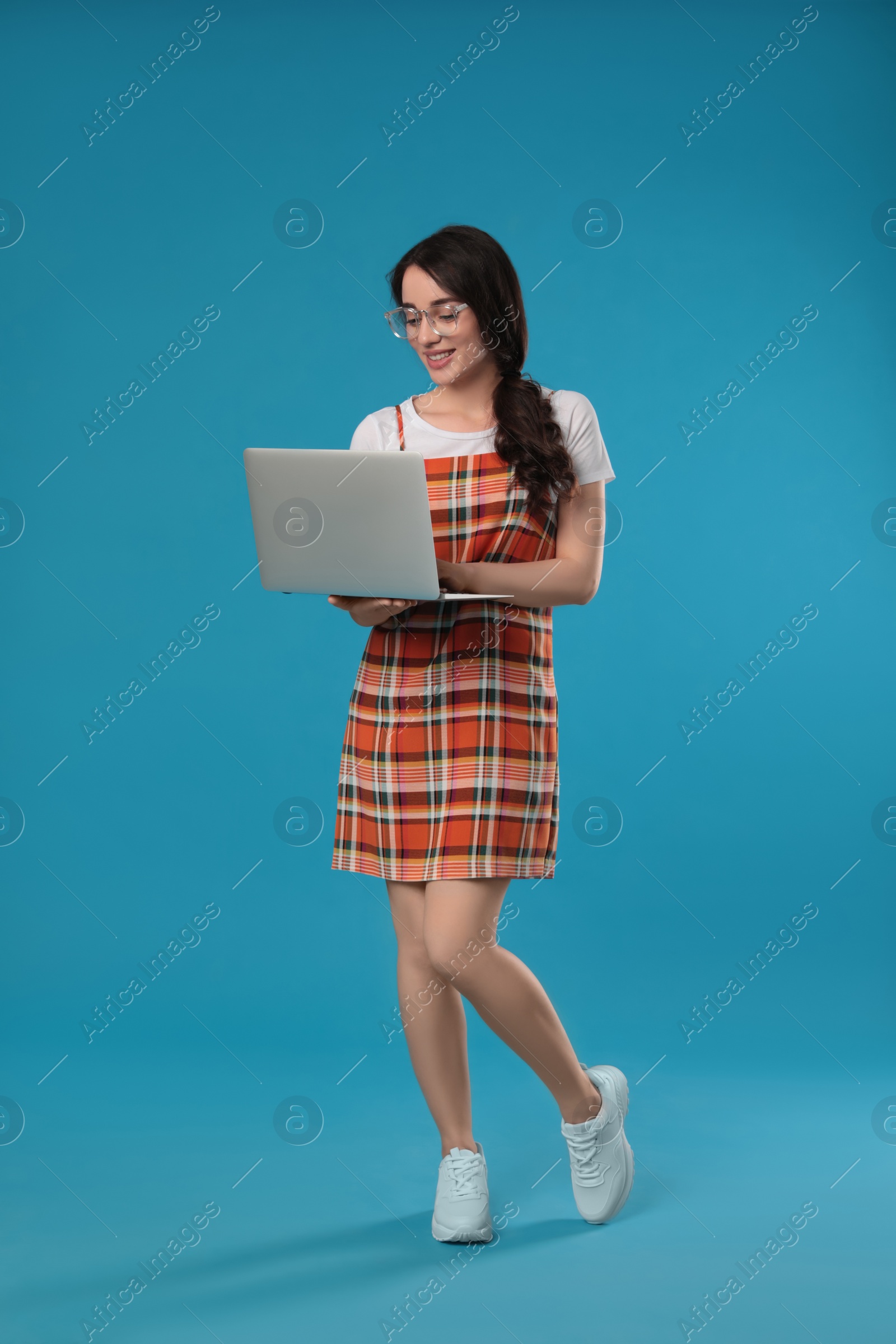 Photo of Young woman with laptop on blue background