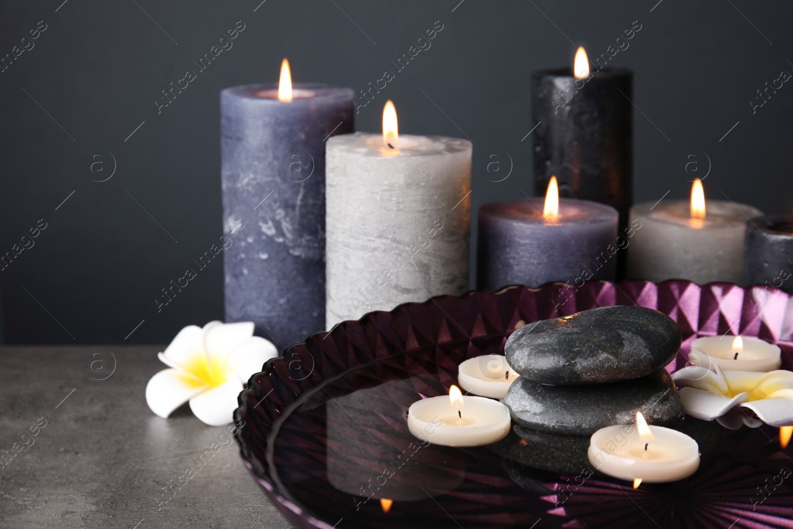 Photo of Spa composition with burning candles and water in plate on table, space for text