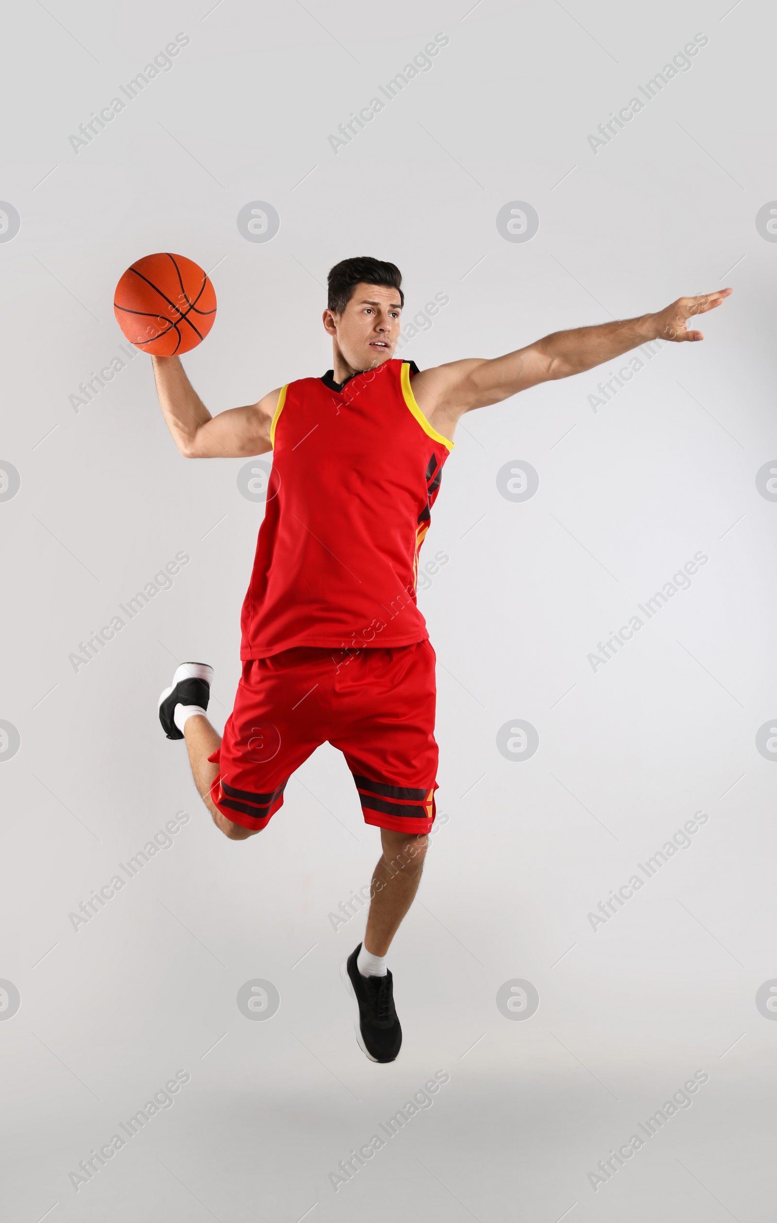 Photo of Professional sportsman playing basketball on grey background