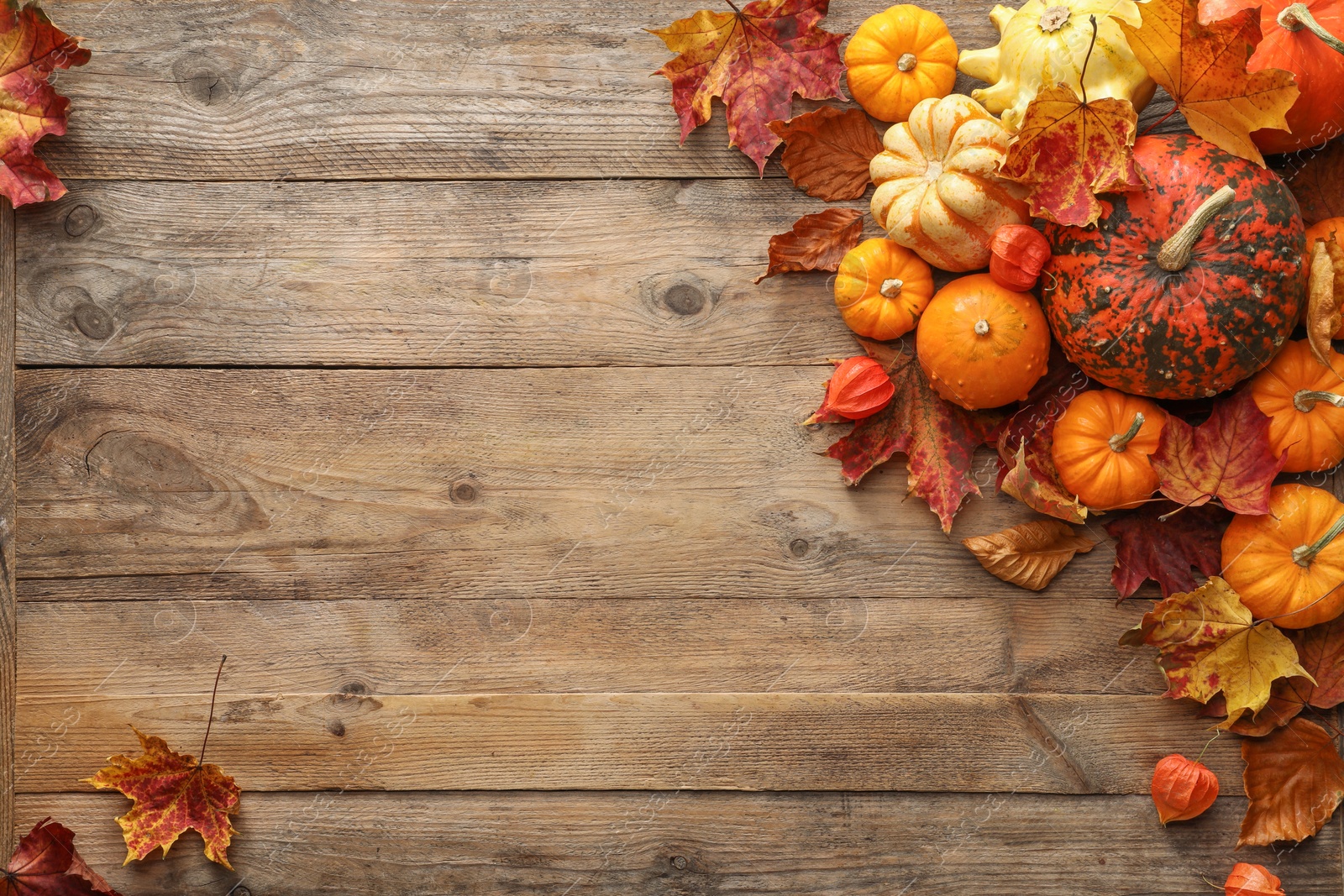 Photo of Dry autumn leaves and pumpkins on wooden table, flat lay. Space for text