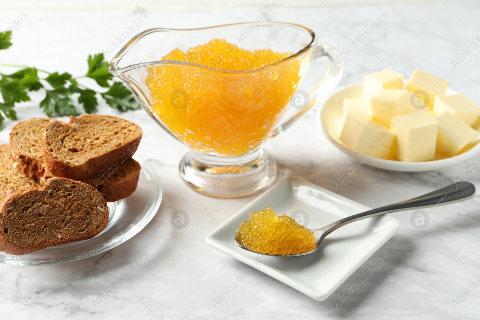 Photo of Fresh pike caviar, butter, bread and parsley on white marble table