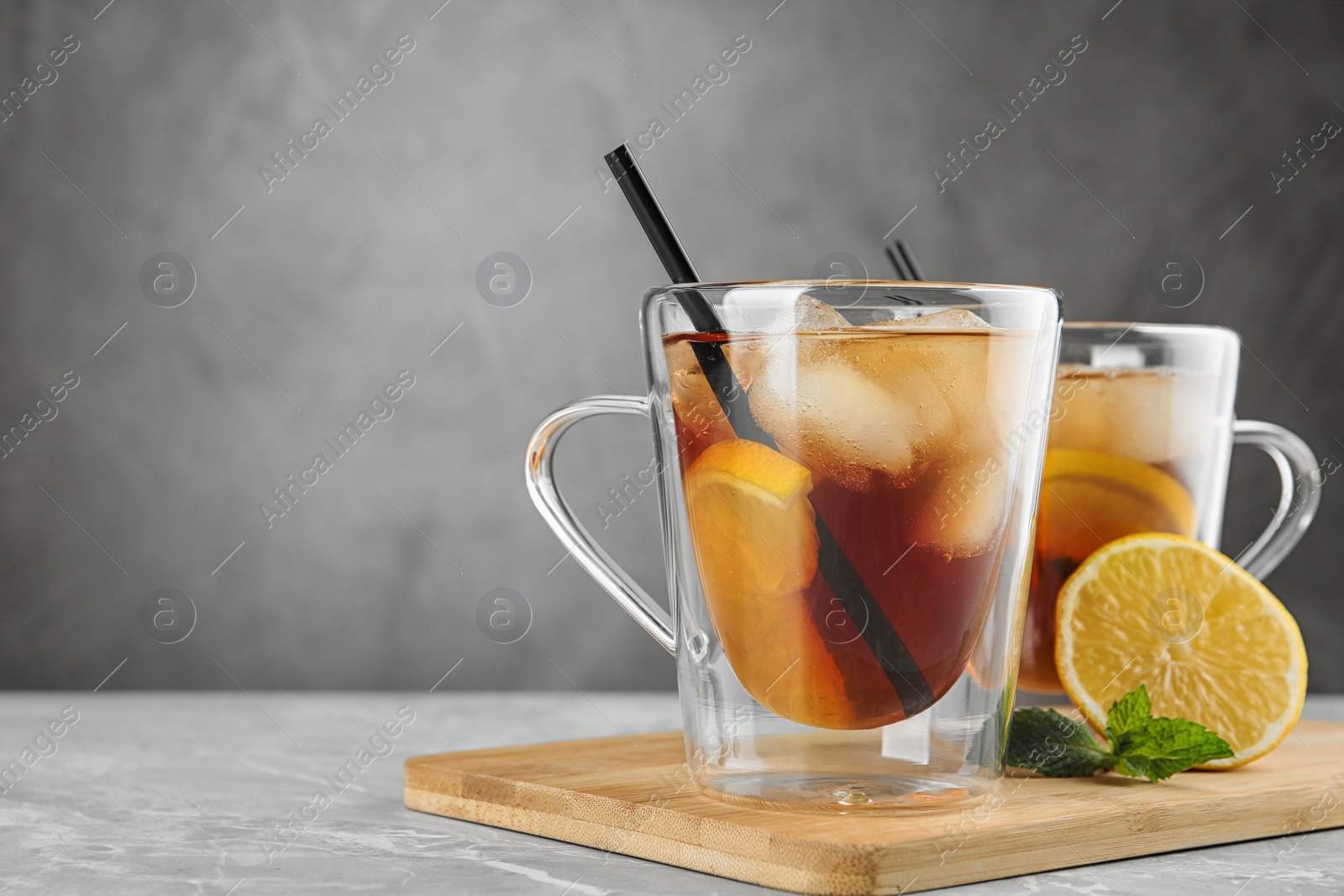 Photo of Cups of refreshing iced tea on marble table against grey background. Space for text