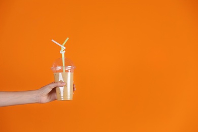 Photo of Young woman holding plastic cup of healthy smoothie on color background