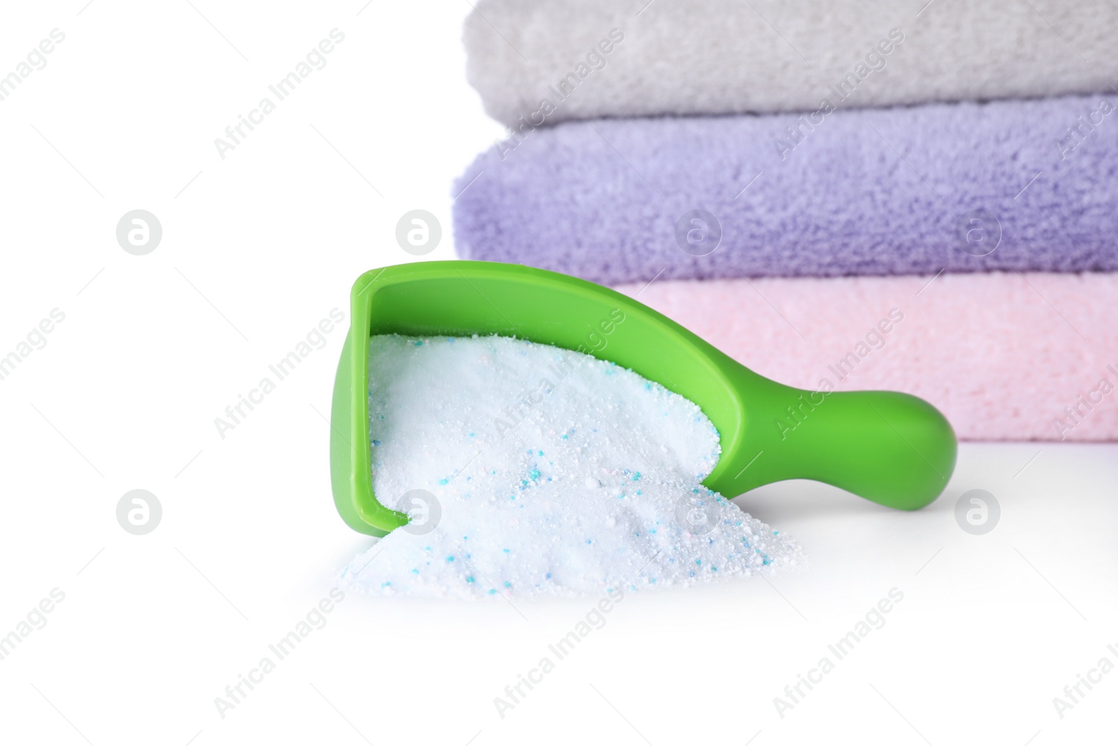 Photo of Laundry detergent in plastic measuring scoop and towels on white background