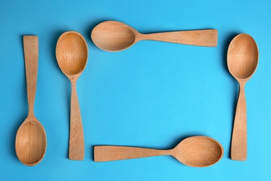 Photo of Clean empty wooden spoons on blue background, flat lay. Space for text