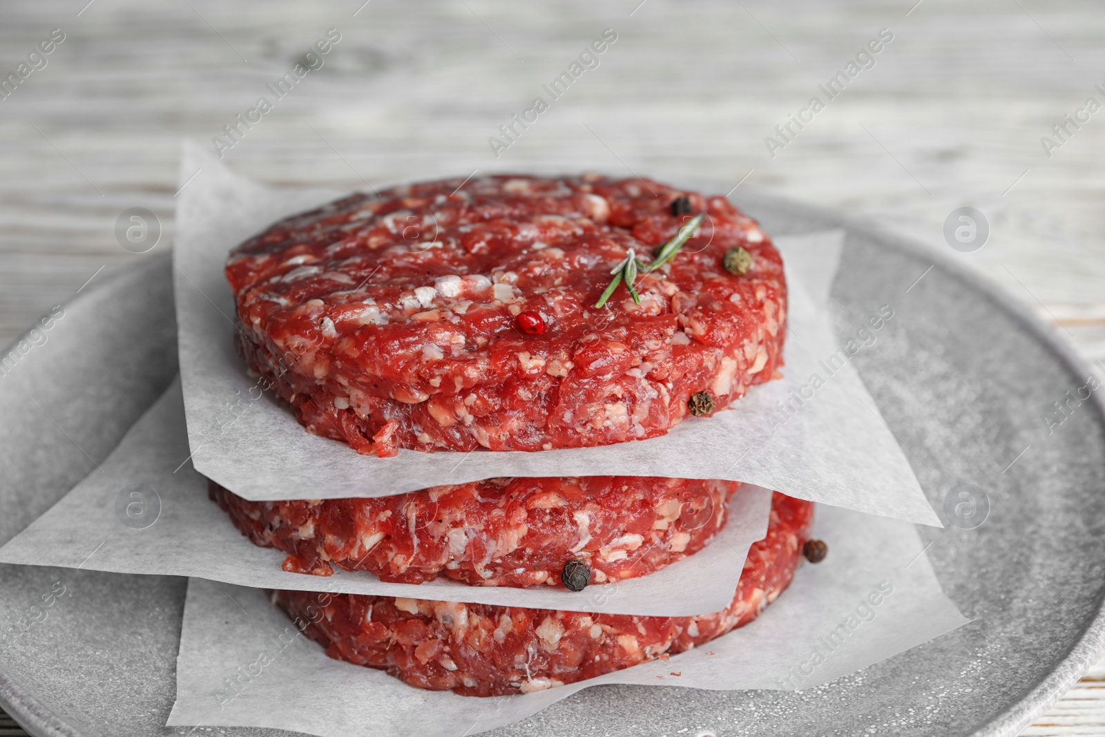 Photo of Raw meat cutlets for burger on white wooden table, closeup