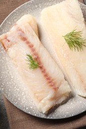 Pieces of raw cod fish and dill on table, top view