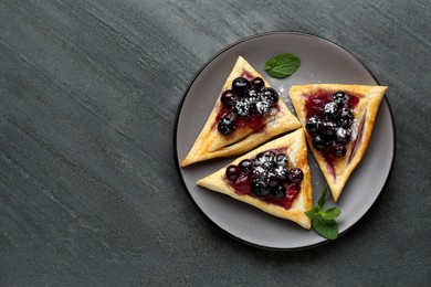 Fresh tasty puff pastry with sugar powder, jam, sweet berries and mint on grey table, top view. Space for text