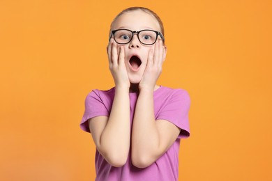 Photo of Portrait of emotional girl in glasses on orange background