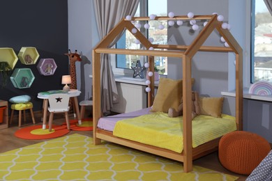 Photo of Stylish child room interior with comfortable house bed and toys