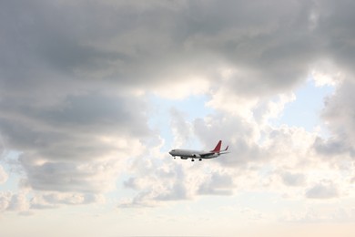 Photo of Modern white airplane flying in sky with clouds