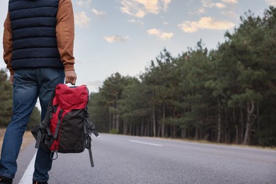 Man with backpack going along road, closeup