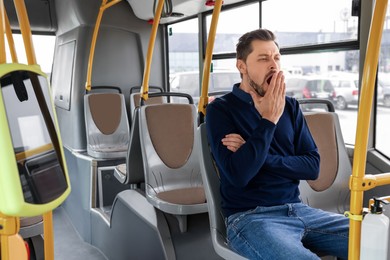 Sleepy tired man yawning in public transport