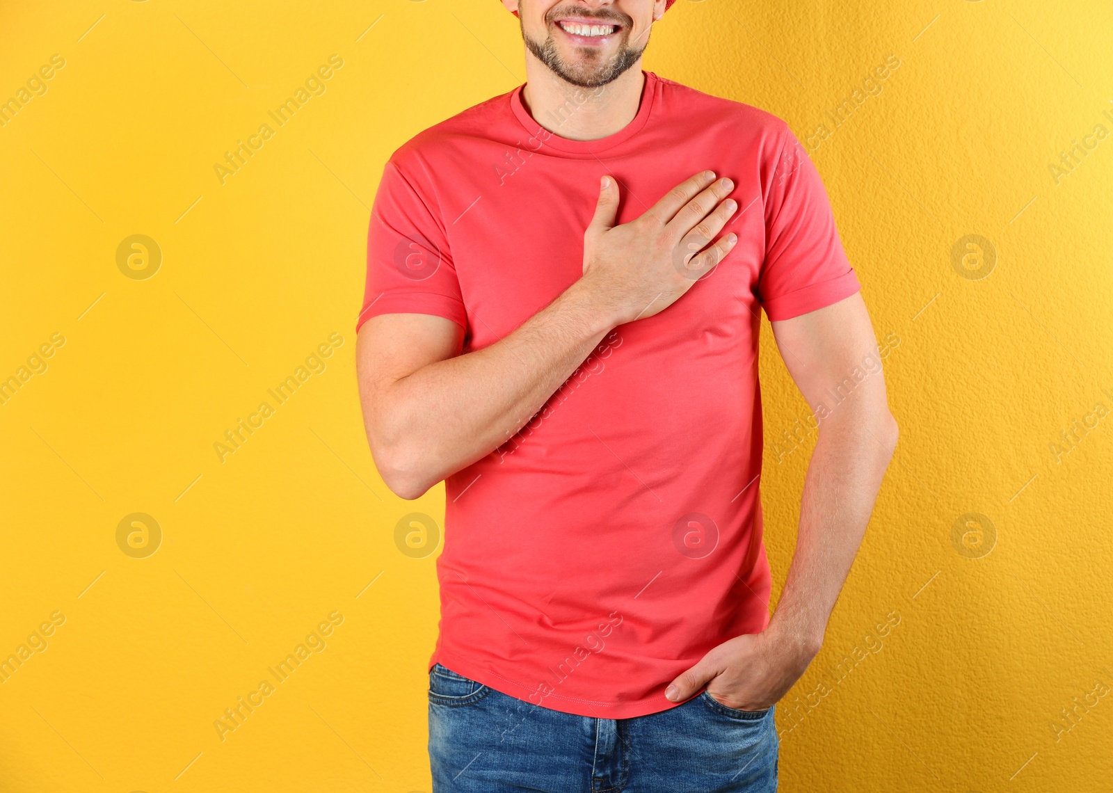 Photo of Man holding hand near his heart on color background, closeup