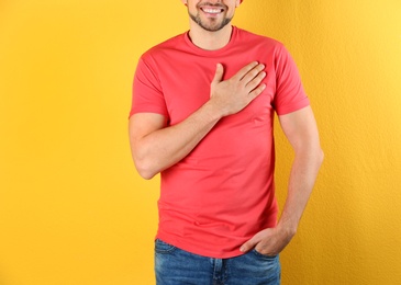 Man holding hand near his heart on color background, closeup