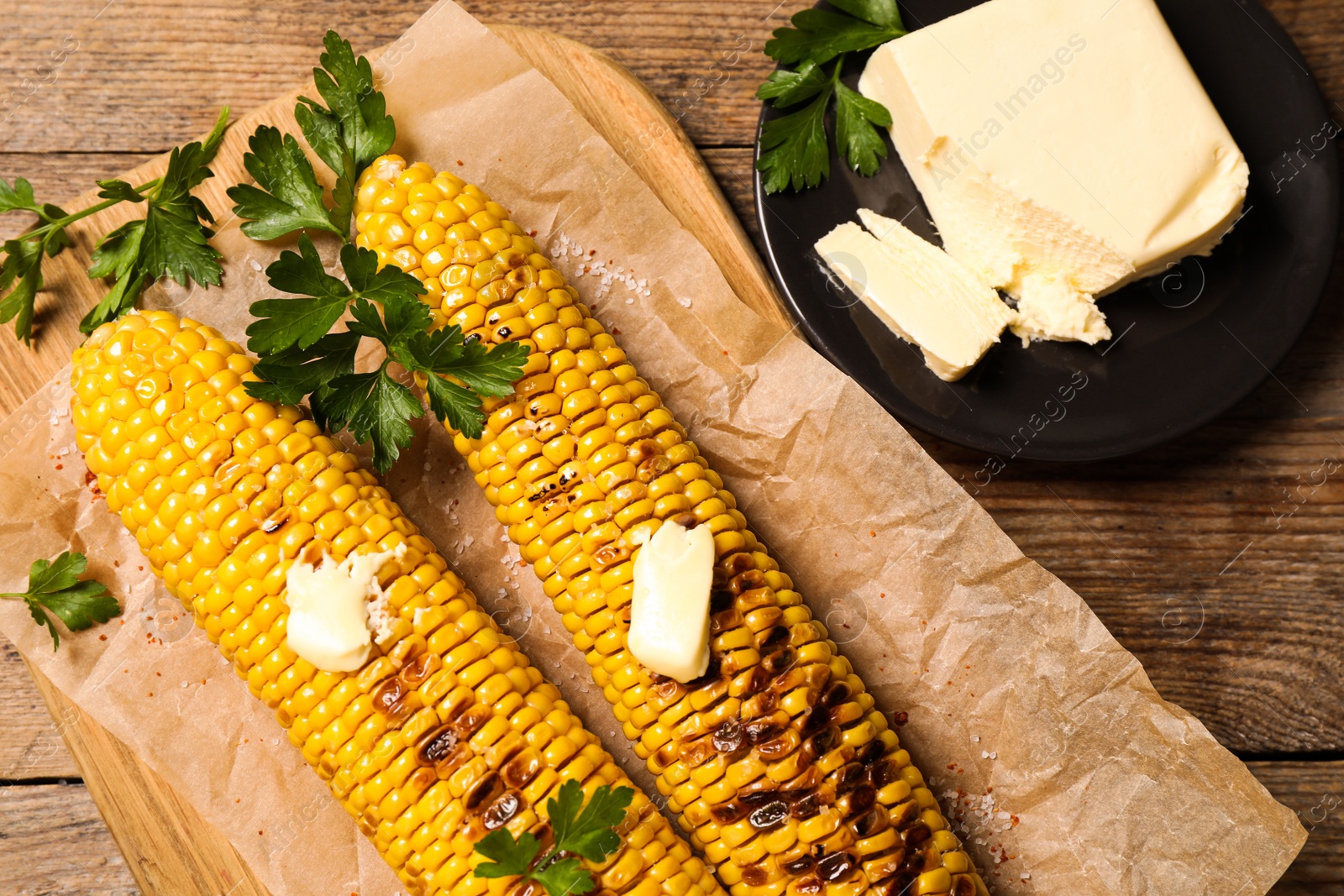 Photo of Tasty grilled corn on wooden table, flat lay