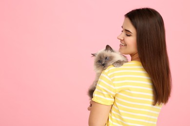Photo of Happy woman with her cute cat on pink background, space for text