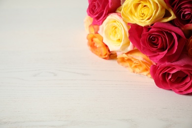 Photo of Luxury bouquet of fresh roses on white wooden table, closeup. Space for text
