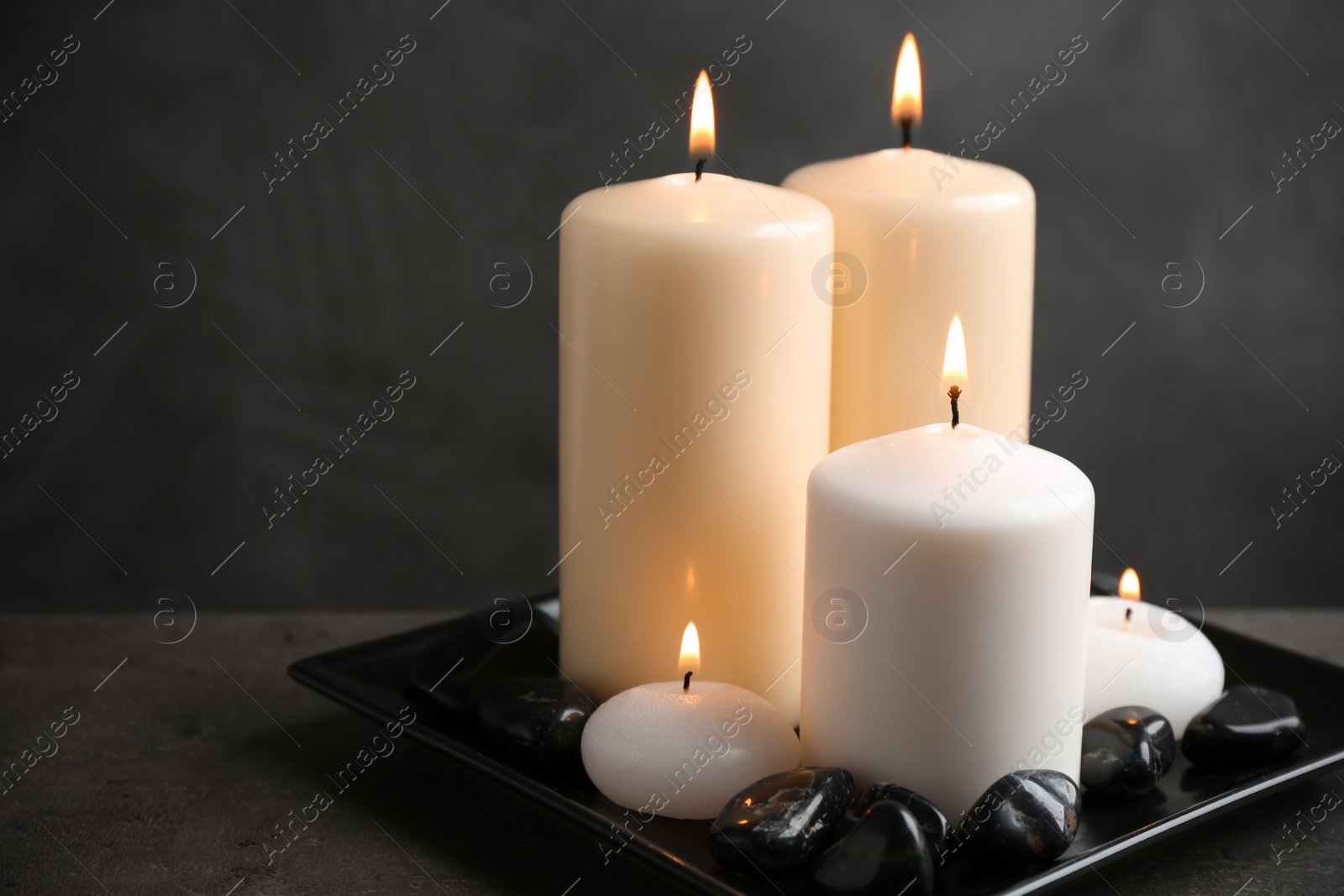 Photo of Plate with color candles and rocks on table, space for text