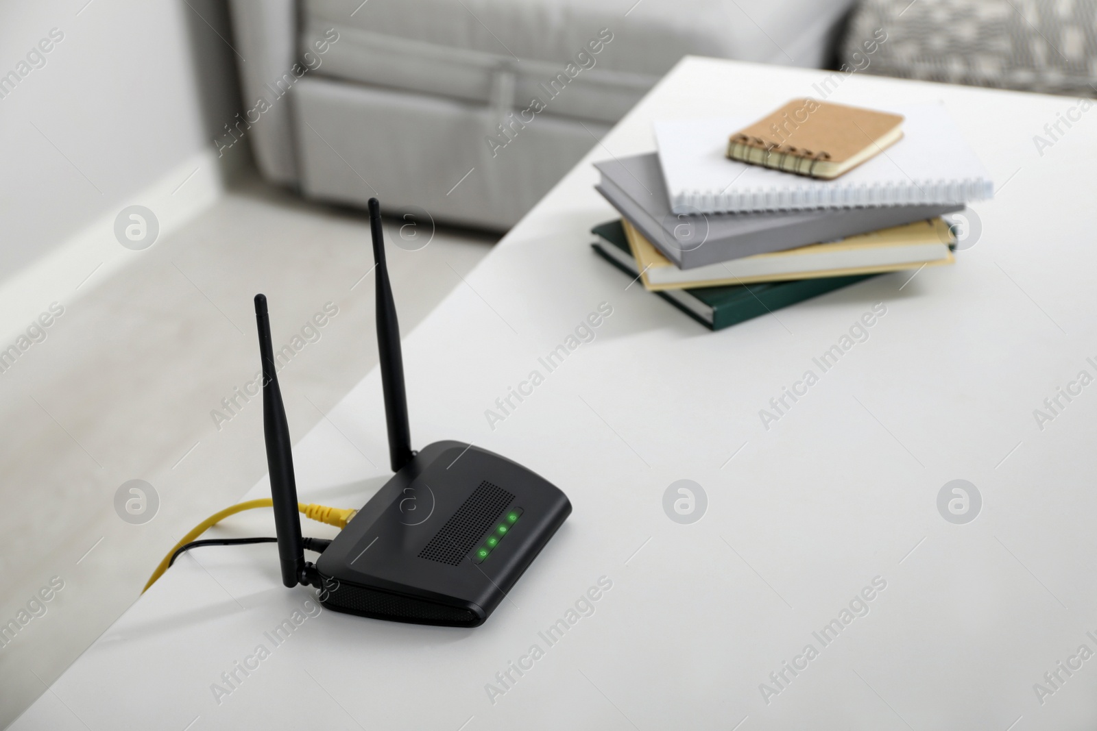 Photo of Modern Wi-Fi router on white table in room. Space for text