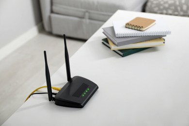 Modern Wi-Fi router on white table in room. Space for text