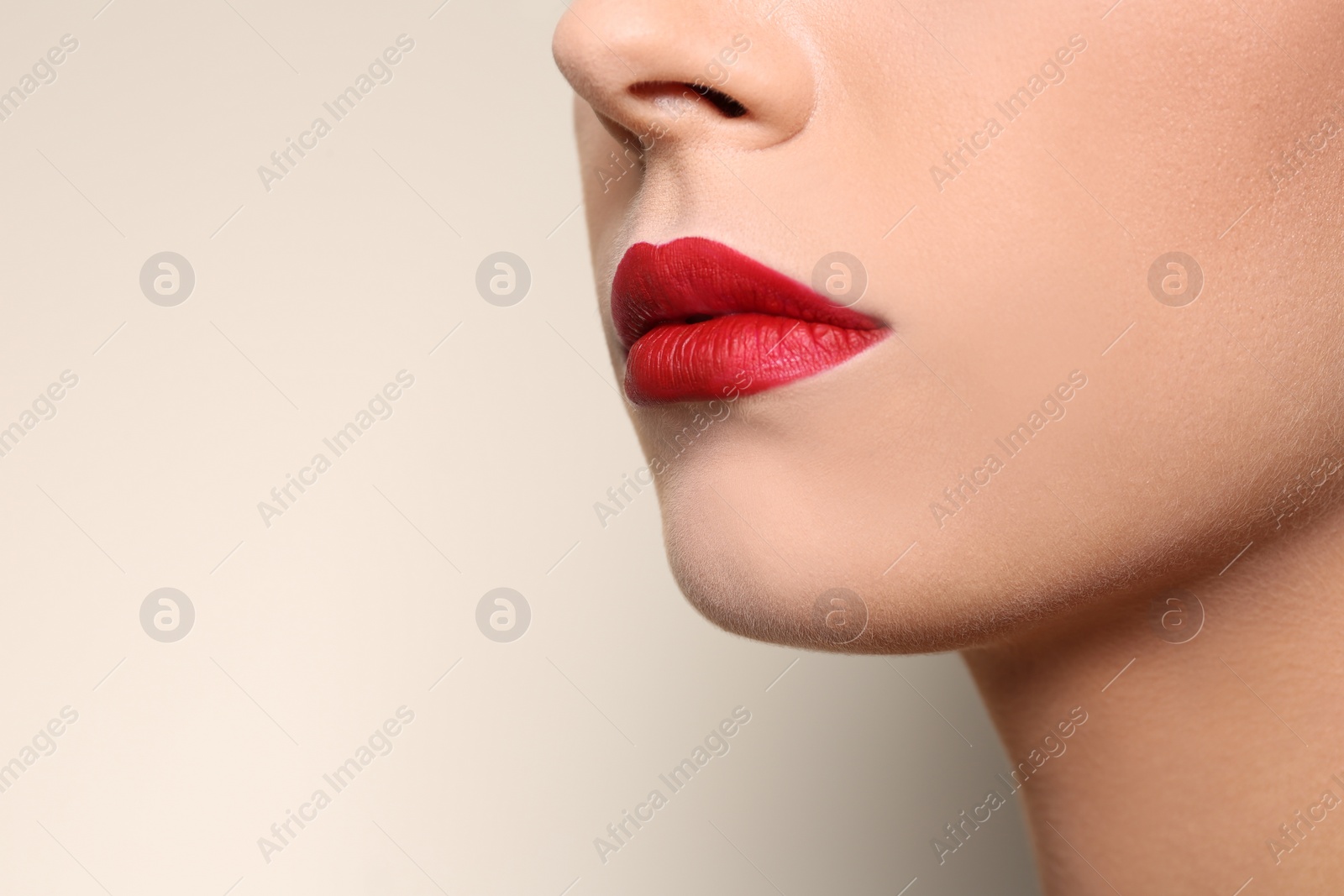 Photo of Beautiful young woman with red lips on color background, closeup. Space for text