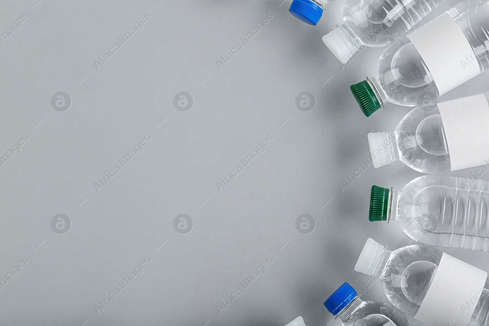 Photo of Bottles of water on light background, top view. Space for text