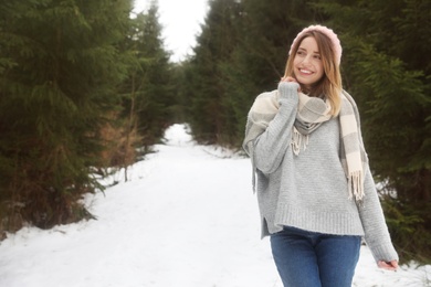 Photo of Young woman in snowy conifer forest, space for text. Winter vacation