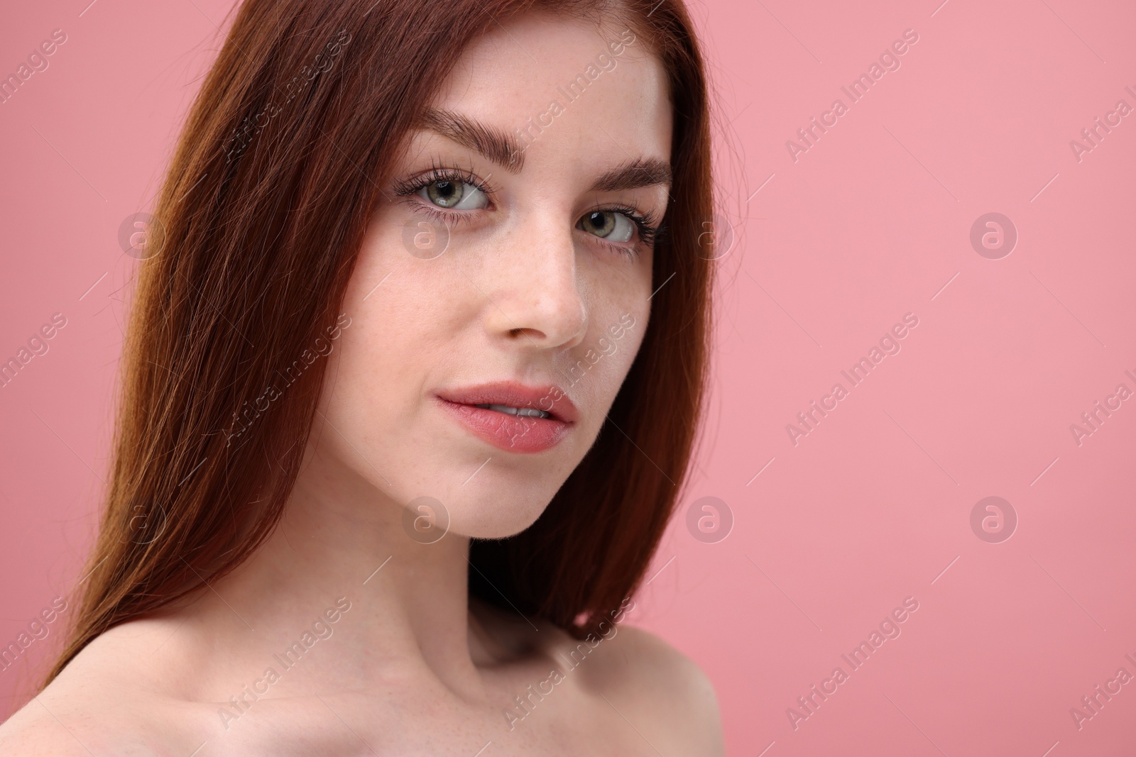 Photo of Portrait of beautiful woman with freckles on pink background, closeup. Space for text