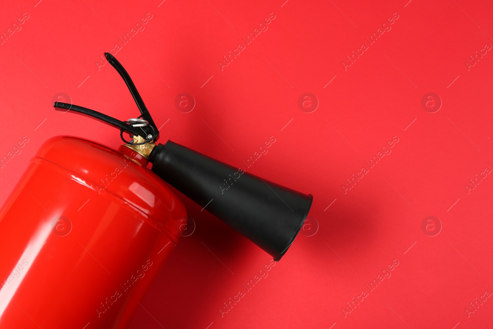 Photo of Fire extinguisher on red background, top view. Space for text