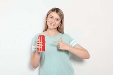 Beautiful happy woman holding red beverage can on light background